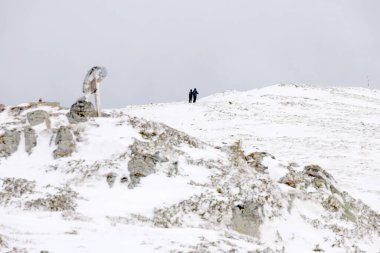 Trekking uphill in winter mountains, through snow and heading to mountaintop. Concept of mountaineering, alpinism and alpine climbing