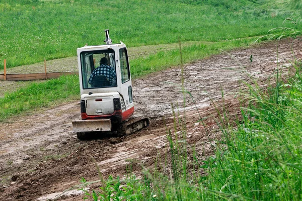 建設現場で泥の中で作業する小容量の白いブルドーザー — ストック写真