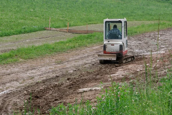 建設現場で泥の中で作業する小容量の白いブルドーザー — ストック写真