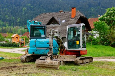 İnşaat alanında mini kazıcı. Toprak işçileri için kompakt inşaat ekipmanı. Toprak işleri için vazgeçilmez bir asistan.