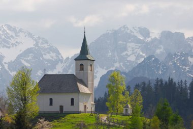Slovenian mountain landscape and cute small church on the hill. St Spirit ( Sveti Duh) church and Kamnik-Savinja Alps in background, Slovenia, Europe