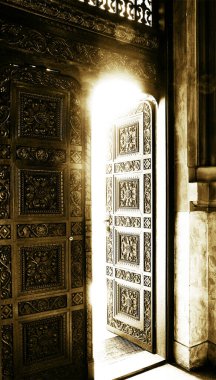 Light entering a dark room through a door in an ancient cathedral clipart