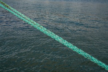 Demir atmış bir geminin eski yeşil denizcilik ipinin soyut görüntüsü.