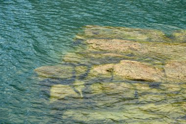 Gölün yüzeyindeki parlak ve yansıtıcı su. Bir gölün ya da küçük dalgalı deniz suyunun soyut arkaplanı. Su dokusu