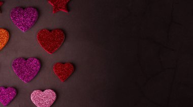 Soyut gri arka plana karşı ışıltılı kalpleri olan Sevgililer Günü afişi ve metin için yeri olan bir çelenk. Sevgililer Günü 'nün şenlikli arka planı.