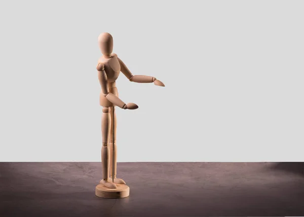 A wooden mannequin Standing on a dark grey table. Wooden Drawing Doll with Empty Space.