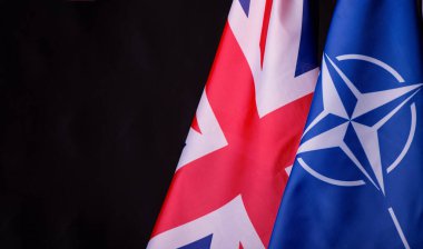 Ukrayna, Kiev - 10.04.2023. Birleşik Krallık ve NATO resmi bayrakları siyah arka plana karşı. Belirsizlik ve Çatışma Dünyasında Birlik ve Dayanıklılık Sembolü.