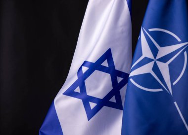 Ukrayna, Kiev - 10.04.2023. İsrail ve NATO resmi bayrakları siyah arka plana karşı. Belirsizlik ve Çatışma Dünyasında Birlik ve Dayanıklılık Sembolü.