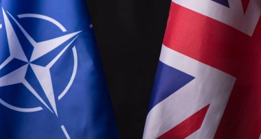 Ukrayna, Kiev - 10.04.2023. Birleşik Krallık ve NATO resmi bayrakları siyah arka plana karşı. Belirsizlik ve Çatışma Dünyasında Birlik ve Dayanıklılık Sembolü.