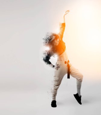 Parlak sarı pantolon giyen çekici bir kadın beyaz arka planda havaya zıplıyor. Dağılım ve ışık kadınların vücut siluetine etki ediyor..