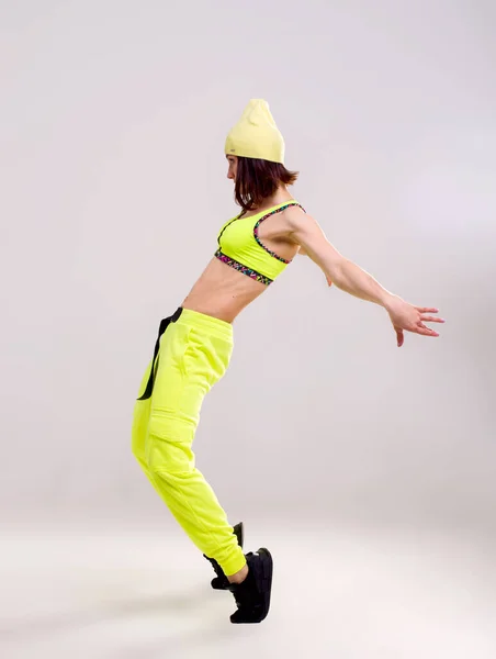 穿着鲜艳的黄色裤子的迷人的女运动健将在白底空中跳跃 散射光和照明弹对妇女身体轮廓的影响 — 图库照片