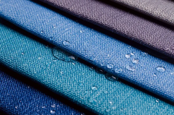 Close up water drop on gunny textile. Concept for easy clean, waterproof surfaces. Multicolor Fabric texture background.