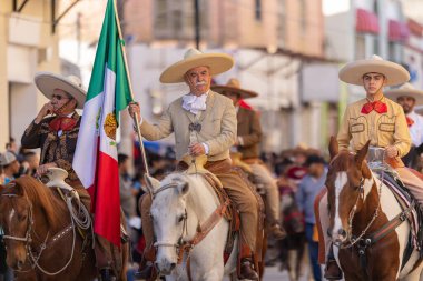 Matamoros, Tamaulipas, Meksika - 26 Kasım 2022: The Desfile del 20 de Noviembre, Charro giyimli atlara binen adamlar, Meksika Bayrağını taşıyorlar.