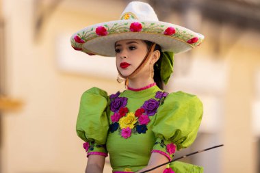 Matamoros, Tamaulipas, Meksika - 26 Kasım 2022: The Desfile del 20 de Noviembre, geleneksel charro kıyafetleri giyen genç bir kadın, geçit töreninde ata biniyor.