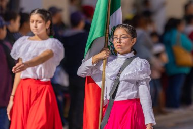 Matamoros, Tamaulipas, Meksika - 26 Kasım 2022: The Desfile del 20 de Noviembre, Meksika bayrağına eşlik eden geleneksel kıyafetler giyen genç kadın