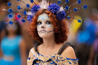 Matamoros, Tamaulipas, Meksika - 1 Kasım 2022: Dia de los Muertos Parade, Catrina geleneksel kıyafet ve çiçek başlıklı elbise giyiyor