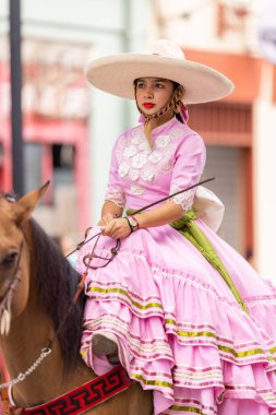 Matamoros, Tamaulipas, Meksika - 16 Eylül 2022: Desfile 16 de Septiembre, geleneksel kıyafet giyen genç kadın ata biniyor
