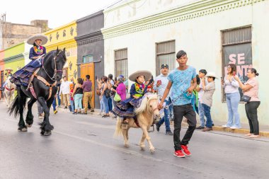 Matamoros, Tamaulipas, Meksika - 25 Şubat 2023: Fiestas Mexicanas Parade, geleneksel Meksika kıyafetleri giyen kız geçit töreninde ata biniyor