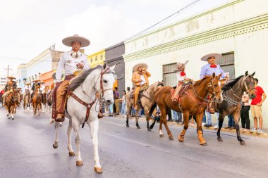 Matamoros, Tamaulipas, Meksika - 25 Şubat 2023: Fiestas Mexicanas Parade, geleneksel Meksika kıyafetleri giyen adamlar geçit töreninde ata biniyorlar