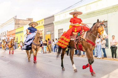 Matamoros, Tamaulipas, Meksika - 25 Şubat 2023: Fiestas Mexicanas Parade, geleneksel Meksika kıyafetleri giyen kadınlar geçit töreninde ata biniyorlar