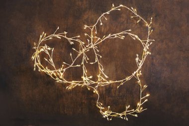 Christmas lights on adark woodeen background. Golden Xmas decorations glowin