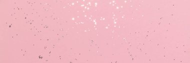 Sparkling silver glitter on pink background banner texture. Abstract holiday blurred lights header. Wide screen wallpaper. Panoramic web banner with copy space for design