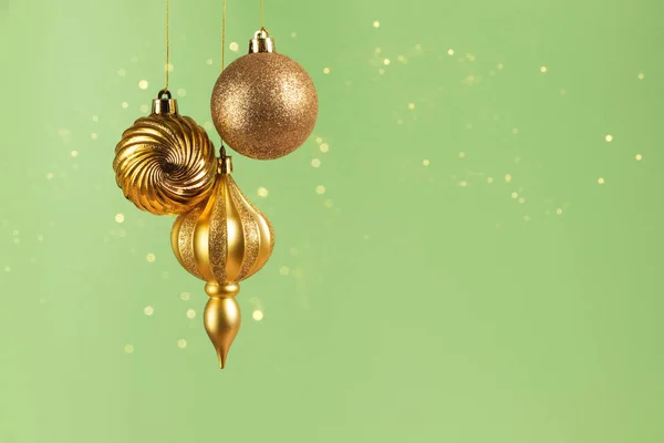 Рождественская Открытка Тремя Золотыми Шариками Украшения Зеленом Фоне Боке Огни — стоковое фото