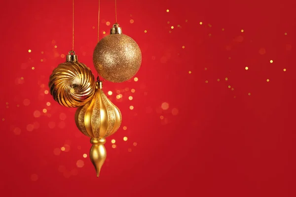 Рождественская Открытка Тремя Золотыми Шариками Украшения Красном Фоне Боке Огни — стоковое фото