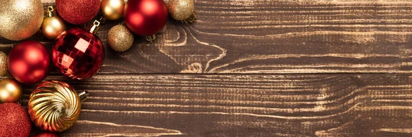 Christmas banner with red and golden decoration balls on wooden background with copy space. Wide panoramic header