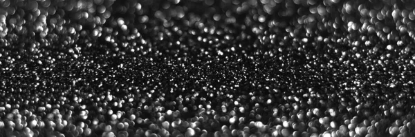 Gray black sparkling glitter bokeh background, abstract defocused texture. Holiday lights. Snowy shiny sparkle stars header. Wide screen wallpaper. Panoramic web banner with copy space