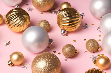 Üzerinde altın ve gümüş toplar ve pembe arka planda konfeti olan Noel kartı