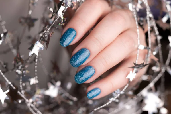 女性的手与美丽的假日美发 蓝色闪亮的指甲与银色扭曲的线与星星 指甲护理概念 — 图库照片