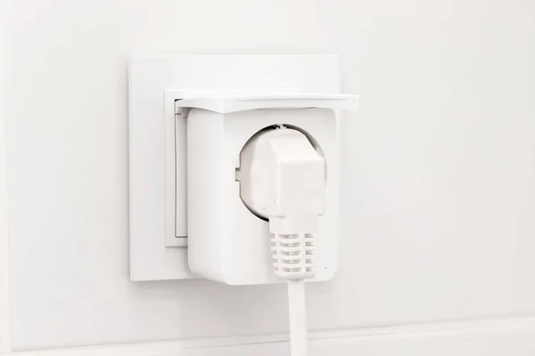 stock image White european electrical outlet with smart plug inserted into it on modern bright bathroom with white tiled wall