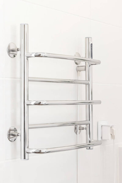 Towel dryer on white tiled wall in modern bathroom