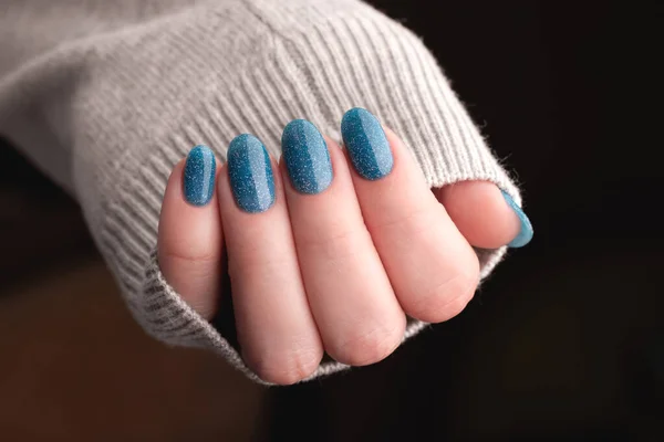 女性的手穿着灰色针织毛衣 有漂亮的修指甲 蓝色闪亮的指甲 指甲护理概念 — 图库照片