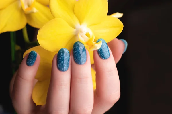 Kobieca Ręka Pięknym Manicure Niebieski Brokat Paznokcie Żółtą Falaenopsis Kwiat — Zdjęcie stockowe