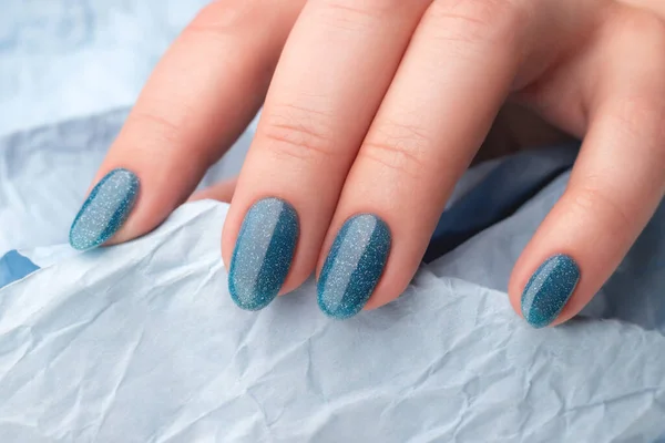 女性的手与美丽的指甲修整 蓝色闪光的蓝色皱纹纸指甲 指甲护理概念 — 图库照片