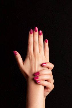 Female hands with beautiful manicure - viva magenta, pink nails on dark black background. Nail, skin care concept