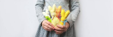 Little girl with colorful bright handmade Easter bunnies in her hands on gray background banner. Panoramic web header with copy space. Wide screen wallpaper