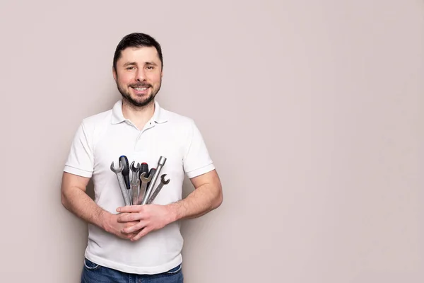Smiling happy bearded man with bouquet of wrenches, spanners and screwdrivers with copy space