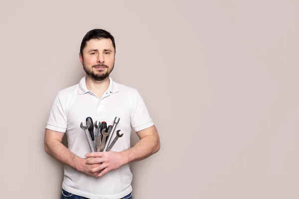 Bearded man with bouquet of wrenches, spanners and screwdrivers with copy space
