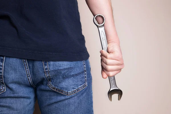 stock image Man holding wrench in one hand. Back view. Ideal for industrial, mechanical, and DIY projects