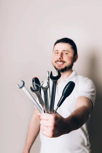 Smiling happy bearded man with bouquet of wrenches, spanners and screwdrivers in one hand. Father\'s Day concept. Focus in the foreground