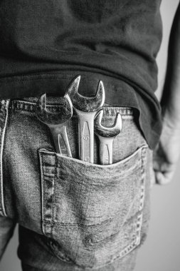 Pantolonunun arka cebinde İngiliz anahtarı olan bir adam. Endüstriyel, mekanik ve DIY projeleri için ideal. Siyah beyaz fotoğraf