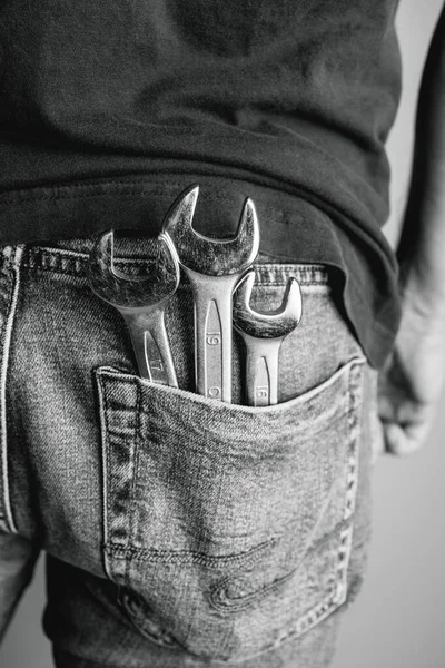 Man with wrenches in back pocket of his jeans. Ideal for industrial, mechanical, and DIY projects. Black and white photo