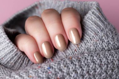 Güzel bir manikürlü kadın eli. Kahverengi, moka köpüklü tırnaklar. Çivi bakımı konsepti. Renk gösterimi, eğilim 2025.