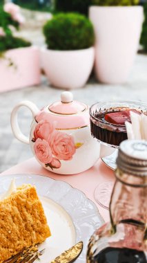 Çiçek desenli zarif çay seti, çaydanlık ve fincan, tabakta bir dilim kek, arka plan..