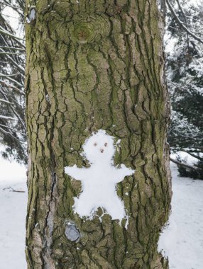 Kardan adam figürü, kışın karla çevrili ağaç kabuğunda yaratıldı..