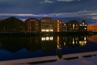 Karlı Trondheim 'da alacakaranlık, Nidelva nehri manzarası ve nehir boyunca eski ahşap binalar. 