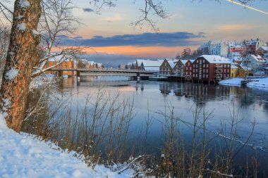 Trondheim 'da kış, Nidelva nehri manzarası ve Bakklandet bölgesindeki tarihi kereste binaları suya yansıdı.